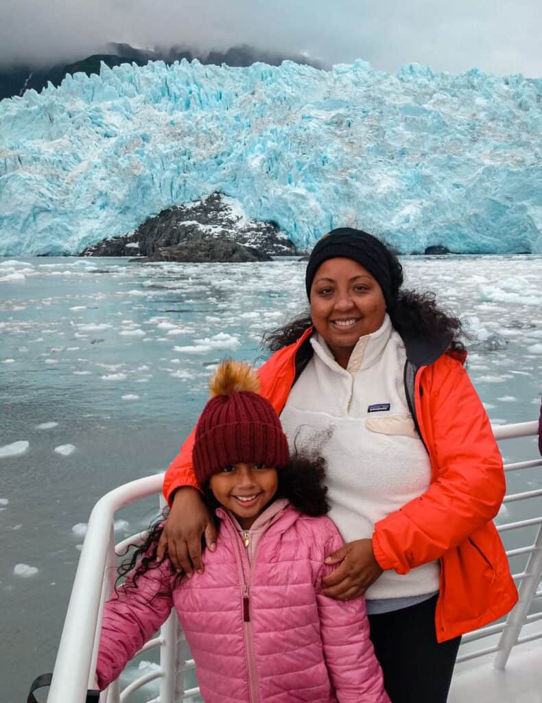 mother and daughter standing on cruise ship with tidewater glacier towering in the background