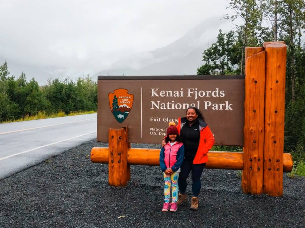 mother and daughter standing in front of Kenai Fjords National Park entrance sign