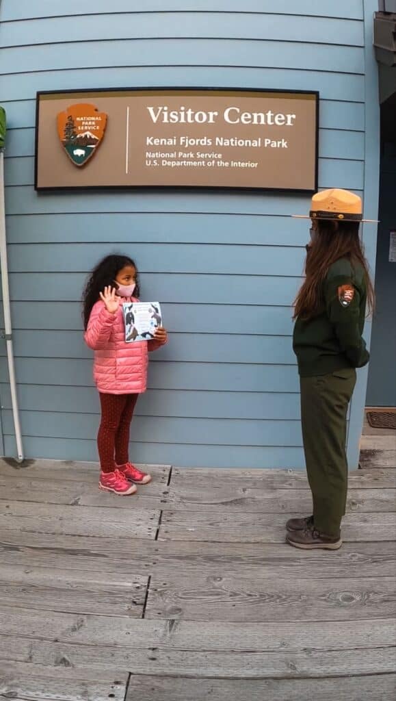 girl taking the Junior Ranger pledge from a National Park Ranger at Kenai Fjords Visitor Center